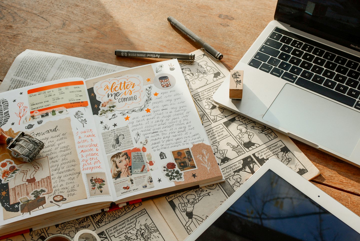 Una scrivania con un laptop, un tablet e un diario aperto.
